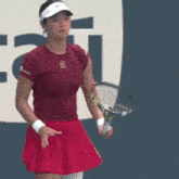 a woman in a red skirt is holding a tennis racquet on a tennis court .