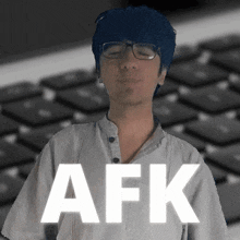 a man wearing glasses is standing in front of a keyboard with the word afk on it