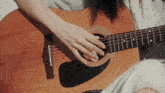 a person playing an acoustic guitar with their hand on the strings
