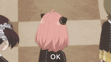 a girl with pink hair is covering her face with her hand .