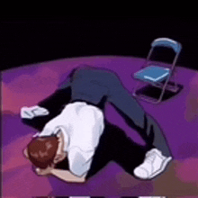 a man is laying on his stomach on a purple floor next to a chair .