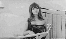 a woman in a black dress is standing in front of a bed .