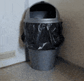 a gray trash can with a black bag on top of it