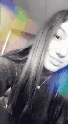 a girl with long hair is taking a selfie with a rainbow behind her .