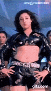 a woman in a crop top and shorts is dancing in front of a group of women .
