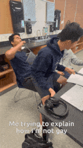 two boys are sitting at a desk and one of them is saying " me trying to explain how i am not gay "