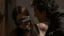 a woman wearing a blindfold is playing with a bunch of rats .