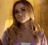 a woman with long blonde hair is making a funny face while wearing a purple shirt .