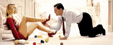 a man is kneeling down and putting a woman 's shoe on her foot