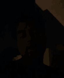 a man 's face is visible in the dark in a dark room