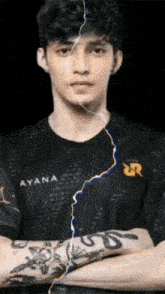 a young man with a tattoo on his arm is standing with his arms crossed and a lightning bolt coming out of his face .