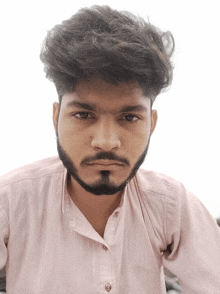 a young man with a beard wearing a pink shirt