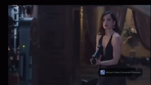 a woman in a black dress is holding a camera in front of a maverick video converter premium screen
