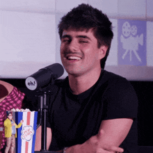 a man is smiling in front of a microphone that says eh on it
