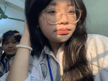 a girl wearing glasses and a white shirt with a blue lanyard around her neck takes a picture