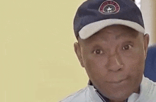 a man wearing a baseball cap and a white jacket is looking at the camera .