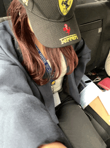 a woman wearing a black ferrari hat sits in the back seat of a car
