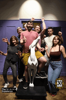 a group of people are posing for a photo with a statue of a dog that says 30 years on it