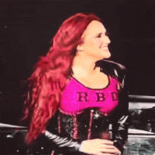 a woman with red hair is wearing a pink top that says rb