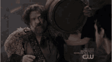 a man holding a barrel in front of a sign that says " batwoman "