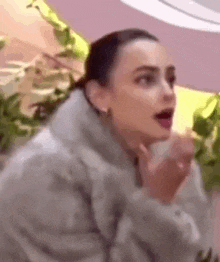 a woman in a fur coat is making a funny face while talking to someone .