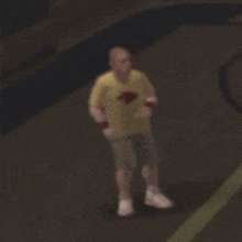 a blurry picture of a man in a yellow shirt and shorts standing on a basketball court .