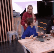 a woman in a blue shirt sits at a table