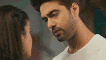 a man and a woman are looking into each other 's eyes and kissing .