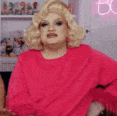 a woman in a pink sweater is standing in front of a neon sign that says " bc "