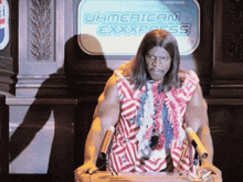 a man stands at a podium in front of a sign that says u.h.american express