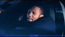 a man with a beard is driving a car