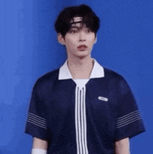 a young man wearing a blue shirt and a headband is standing in front of a blue wall .