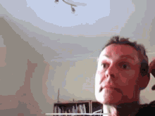 a close up of a person 's face with a bookshelf behind them