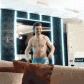 a man without a shirt is standing in front of a mirror
