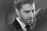 a man in a suit and tie is standing next to a woman in a black and white photo .