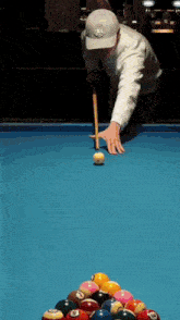 a man in a white hat is playing pool on a table