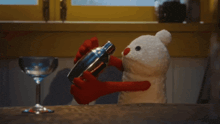 a stuffed teddy bear is shaking a drink in a shaker