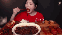 a woman in a red shirt is eating a plate of food