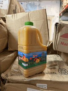 a gallon of mango juice is sitting on top of a pile of cardboard boxes
