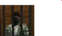 a man wearing a green bandana is behind bars .