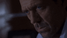 a close up of a man 's face with blue eyes in a dark room