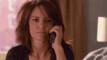 a woman talking on a cell phone with peacock written on the bottom right