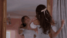 a woman in a white dress is standing in front of a mirror .
