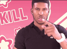 a man in a black shirt points at the camera with the word kill in the background