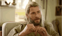 a man with long hair and a beard is sitting on a chair
