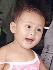 a baby girl wearing a pink tank top with hearts on it