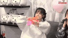 a girl singing into a microphone with joysound written on the bottom right