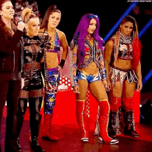 a group of women are standing next to each other on a stage . one of the women has purple hair .