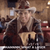 a man in a cowboy hat is sitting at a table with bottles of beer and a napkin .