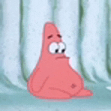 patrick star from spongebob squarepants is sitting in front of a white curtain with a sad look on his face .